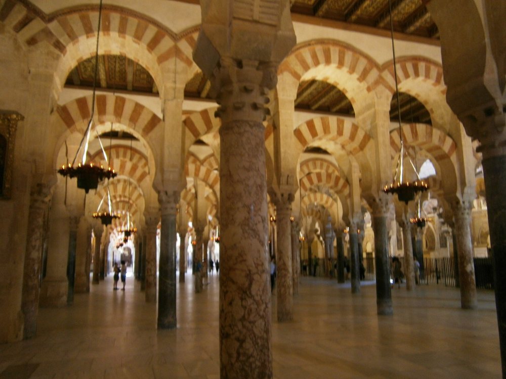Sala muy amplia llena de columnas unidas por arcos dobles de dovelas rojas y blancas
