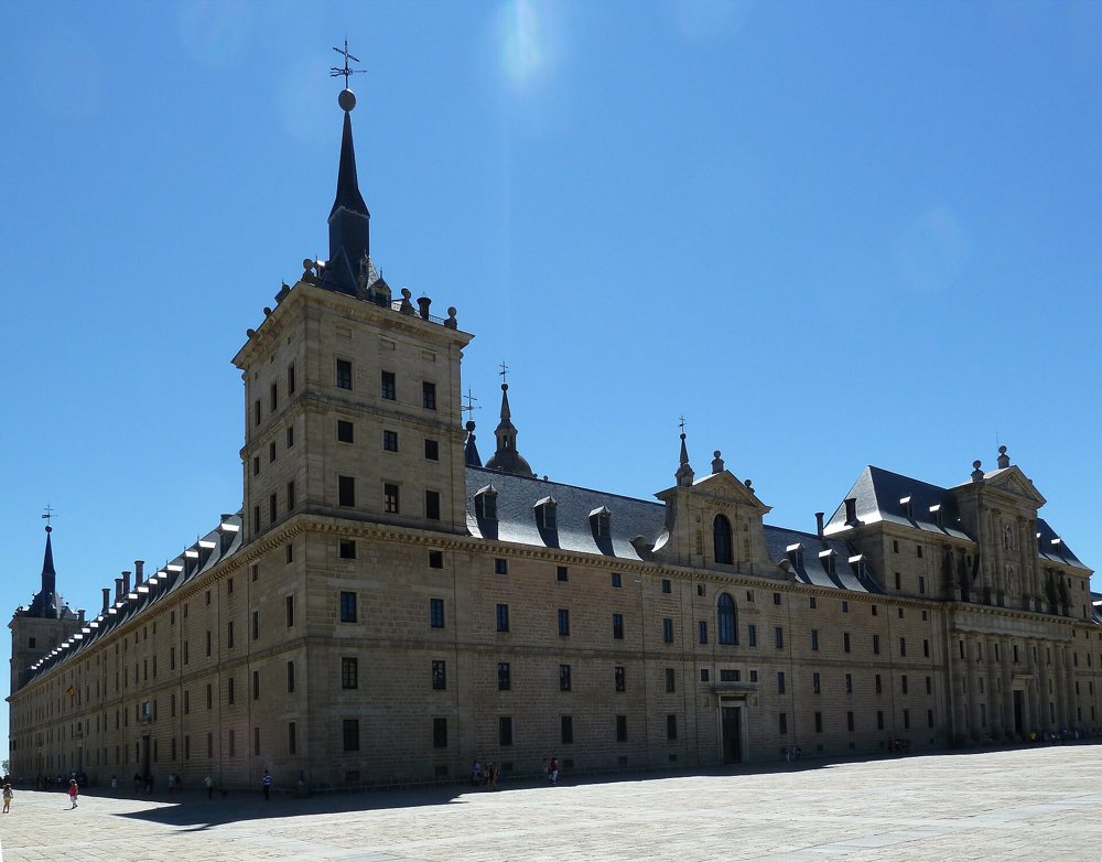 Fachada de granito del monasterio de El Escorial, larga y sobria, con torres en las esquinas y una portada central
