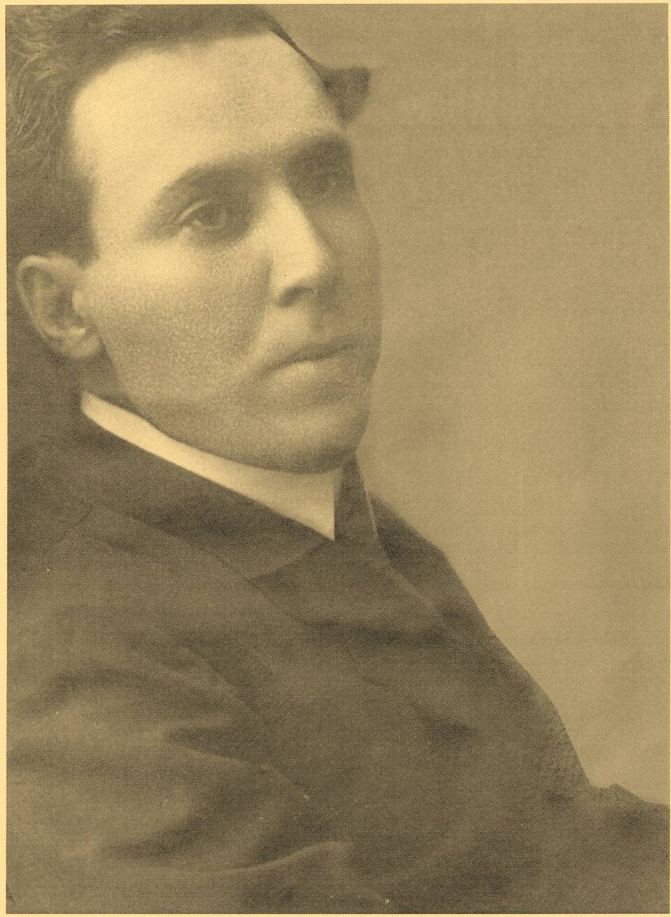 Fotografía en sepia de Antonio Machado, joven y sin barba, con traje oscuro y cuello blanco, mirando de lado