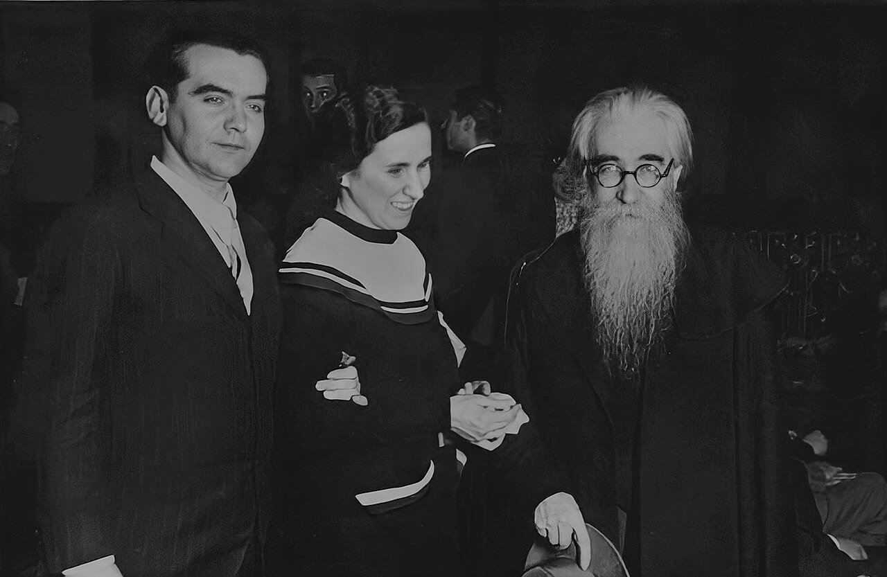 Fotografía en blanco y negro de Federico García Lorca, una mujer y Valle-Inclán, con gafas y larga barba blanca, de pie entre el público de un teatro