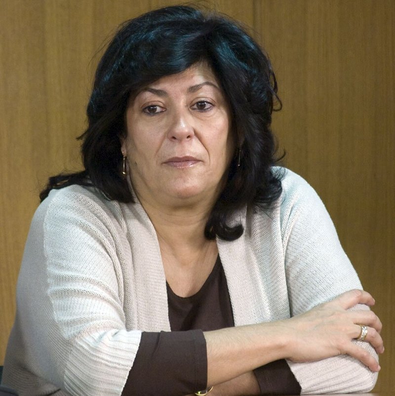 Retrato en color de Almudena Grandes, con el pelo oscuro y ondulado y los brazos cruzados