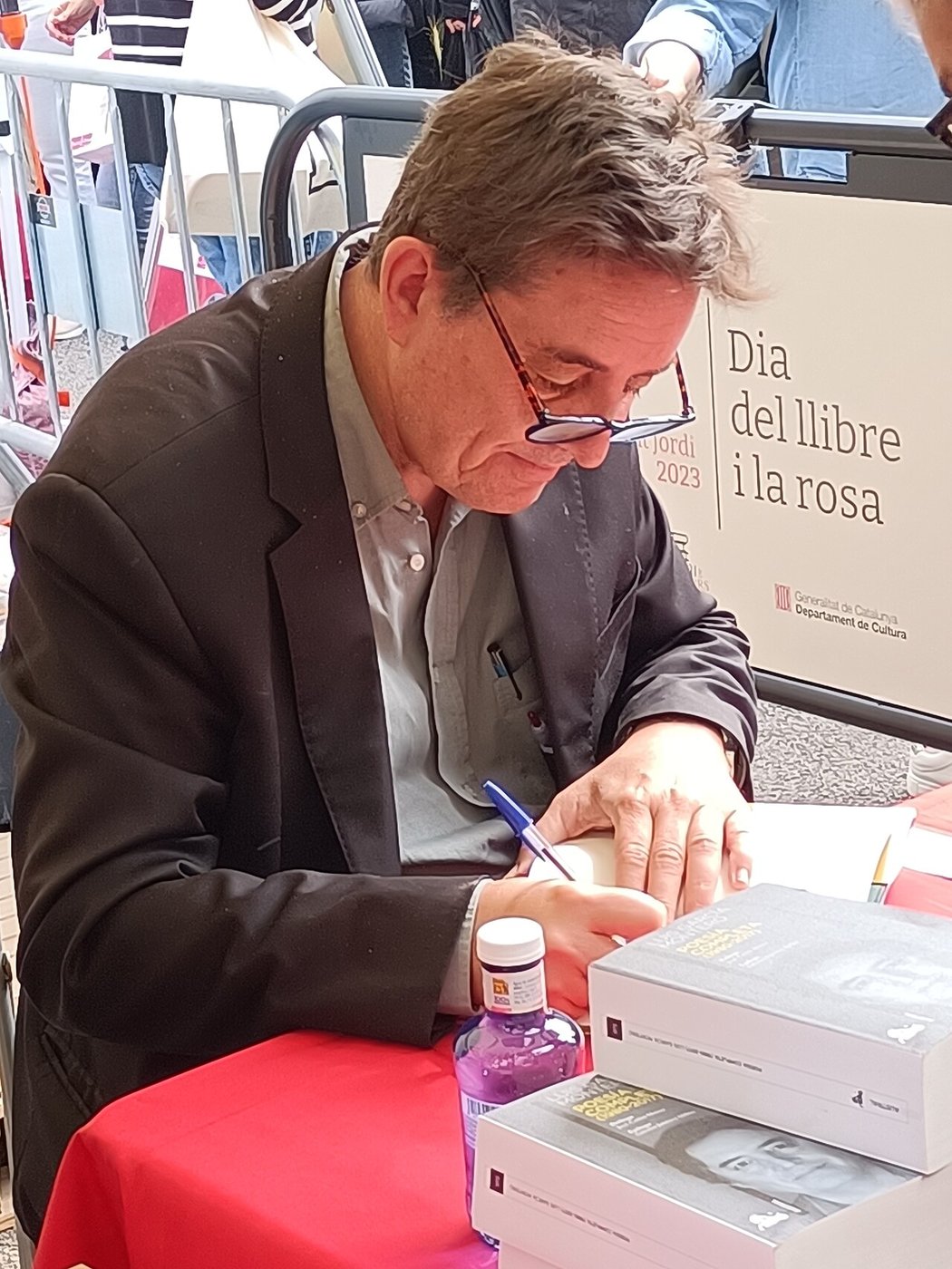 Luis García Montero, con gafas y pelo canoso, sentado en una mesa de firmas